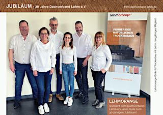 Das Team von Lehmorange steht vor einem Lehmwand