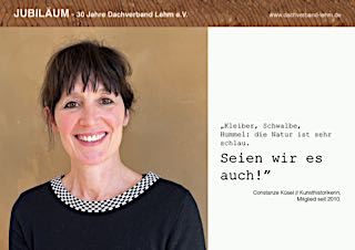 Constanze Küsel, lächelnd vor einem Lehmwand